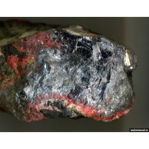 Массивное выделение стально-серого ливингстонита покрытое типичным продуктом изменения минерала - ярко-красной порошковатой киноварью